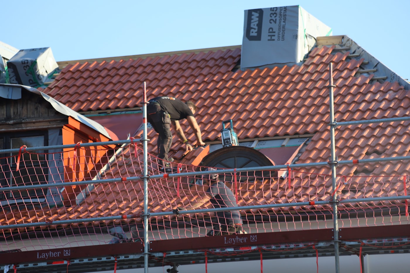 Roofer fastening tile on a steep residential roof
